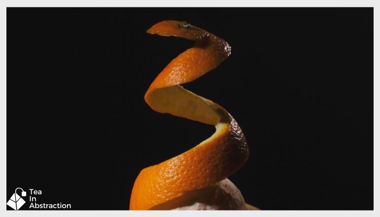 orange peel being removed from and orange against a black background