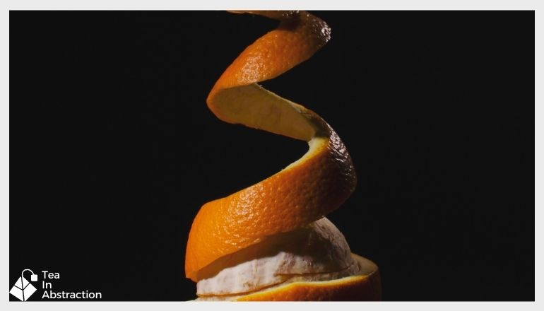 orange peel being pulled off of an orange in a corkscrew fashion
